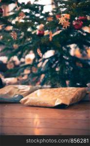 Presents on the wooden floor, under a traditional Christmas tree.