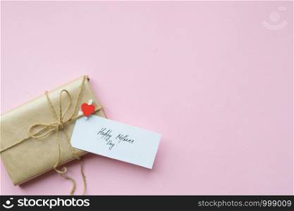 Presents wrapped in brown craft paper and tie hemp string on Light pink background. Gift box with greetings on Mothers Day. Top view. Copyspace. Presents wrapped in brown craft paper and tie hemp string on Light pink background. Gift box with greetings on Mothers Day. Top view.