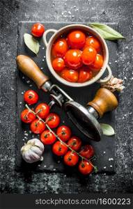Preserved and fresh tomatoes on a stone Board. On dark rustic background. Preserved and fresh tomatoes on a stone Board.