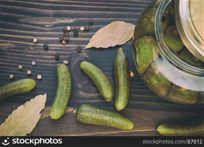 Preserved of Cucumbers: a Still Life of Dried Colorful Pepper (Black, Red, and Green), Bay Leaf, Green Cucumbers and Jars with Vinegar on the Wooden Table