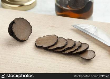 Preserved summer truffle from a pot cut into slices on a cutting board