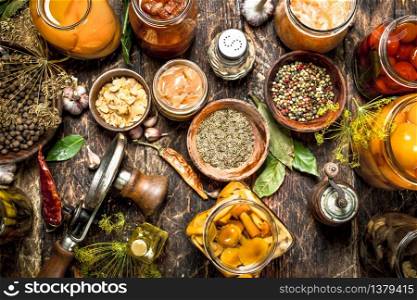 Preserved vegetables in glass jars with seamer. On a wooden background.. Preserved vegetables in glass jars with seamer.