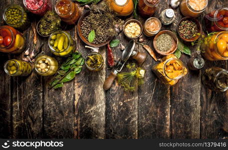 Preserved vegetables in glass jars with seamer. On a wooden background.. Preserved vegetables in glass jars with seamer.