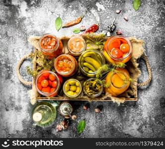 Preserved vegetables with mushrooms on an old tray. On a rustic background.. Preserved vegetables with mushrooms on an old tray.
