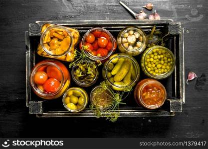 Preserves vegetables in glass jars in an old box. On the black chalkboard.. Preserves vegetables in glass jars in an old box.
