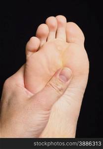 Pressure point massage under foot with thumb isolated towards black