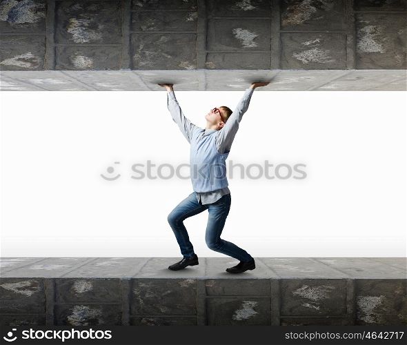 Pressured with circumstances. Young man under pressure between two stone walls