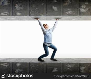 Pressured with circumstances. Young man under pressure between two stone walls