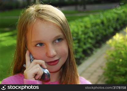 Preteen girl talking on cell phone outside