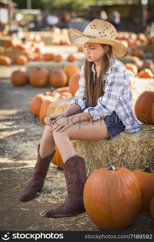 Preteen Girl Wearing Cowboy Hat Portrait at the Pumpkin Patch in a Rustic Setting.