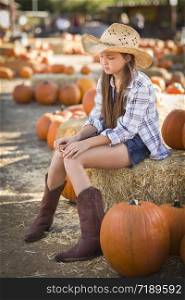 Preteen Girl Wearing Cowboy Hat Portrait at the Pumpkin Patch in a Rustic Setting.