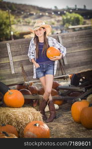 Preteen Girl Wearing Cowboy Hat Portrait at the Pumpkin Patch in a Rustic Setting.