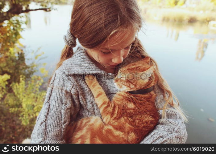 Preteen girl with red cat in her arms.