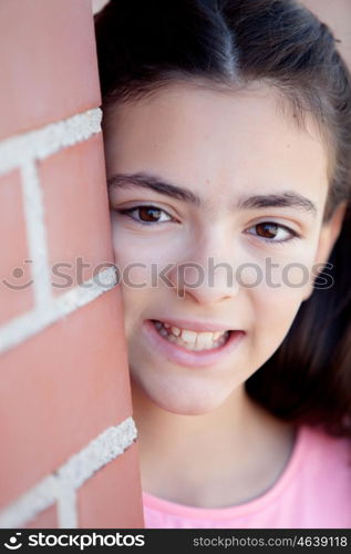 Preteenager girl next to a red brick wall with nice expression