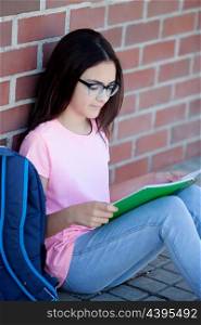 Preteenager girl next to a red brick wall with the backpack sitting on the floor