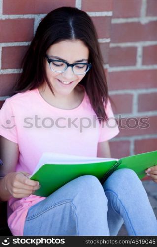 Preteenager girl next to a red brick wall with the backpack sitting on the floor
