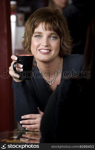 Pretty adult woman with friend in a coffee house