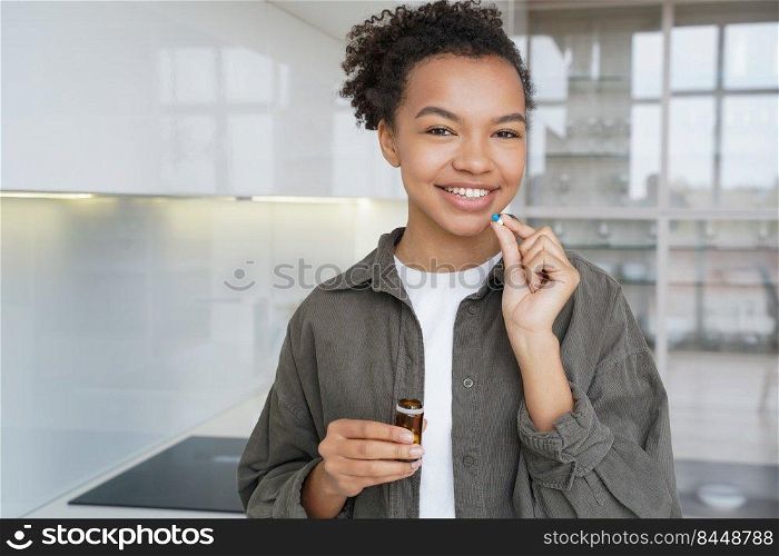 Pretty african american girl is taking capsule. Positive hispanic young woman is taking vitamins or painkillers. Disease prevention and dieting. Contraceptive pills taking. Healthcare concept.. Pretty african american girl is taking capsule. Contraceptive pills taking. Healthcare concept.