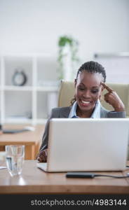 Pretty african business woman working on laptop in office