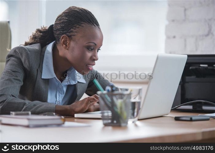 Pretty african business woman working on laptop in office