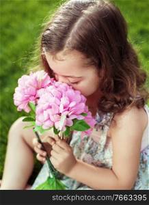 Pretty and cute child holding and sniffing flowers