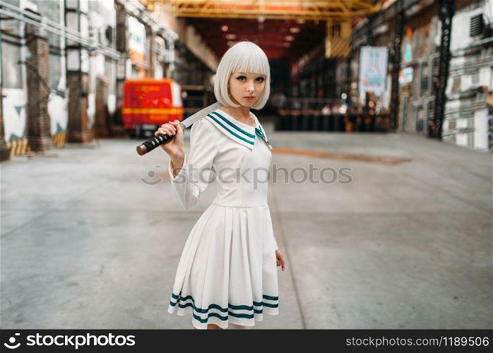 Pretty anime style blonde girl with sword poses on abandoned factory. Cosplay fashion, asian culture, doll with blade, cute woman with makeup. Anime girl with sword poses on abandoned factory