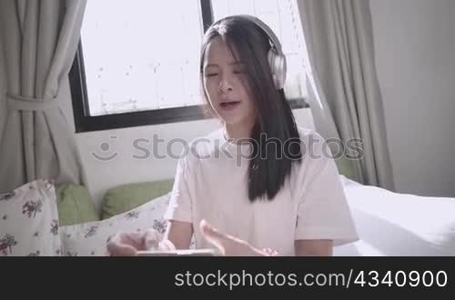 Pretty asian girl doing eport live streaming, internet influencer interact with fan club and her followers, social media star, wearing headphone and casting with smartphone, new normal job at home