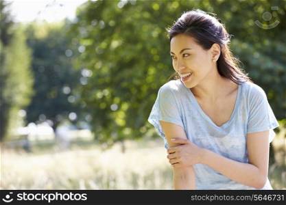 Pretty Asian Woman Sitting On Fence In Countryside