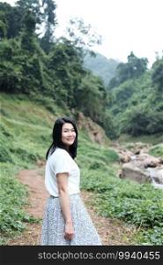 Pretty Asian woman wear white dress is smiling in tropical forest. Freedom life in nature Concept.
