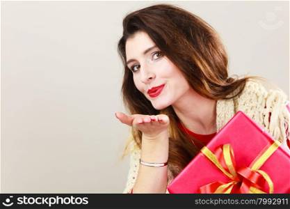 Pretty attractive latin woman holding red box gift blowing kiss on gray. Birthday anniversary christmas concept.