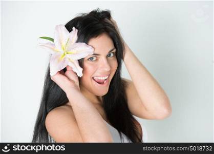Pretty beautiful woman with healthy skin and pink lily in her hairs laughing and looking at camera