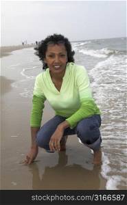 Pretty black woman kneeling by the edge of the waterside
