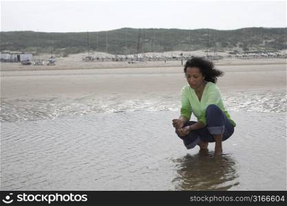 Pretty black woman letting the sand run through her fingers