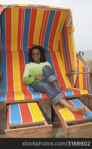 Pretty black woman sitting on a very colorful beachchair