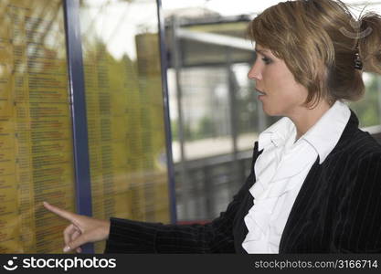 Pretty blond businesswoman checking the trainschedule for the next departing train