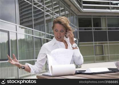 Pretty blond businesswoman looking in shock while her notebook papers are blown about by the wind