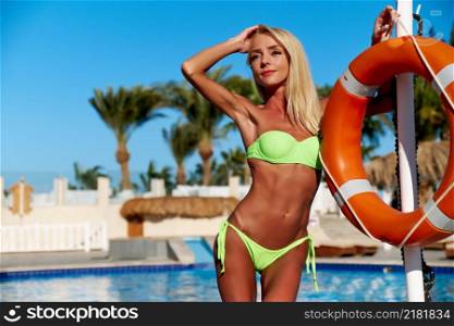 Pretty blond female standing near the pool.. Pretty blond female standing near the pool