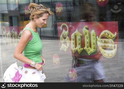Pretty blond girl being tempted by the savings signs of the shoestore