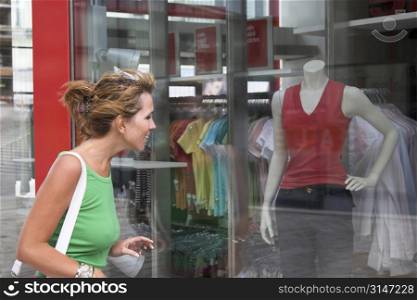 Pretty blond girl checking out the window display of a clothing store