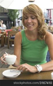 Pretty blond girl enjoying a cup of coffee on the terrace