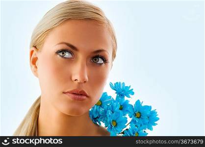 pretty blond girl in a beauty portrait with blue daisy on her shoulder