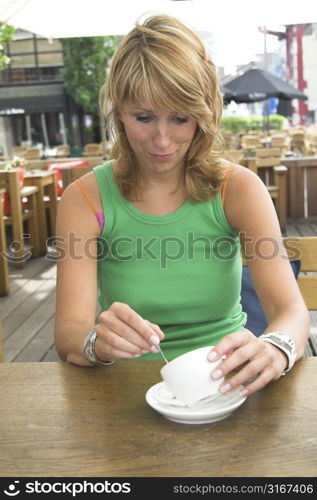 Pretty blond girl pulling a face because her coffeecup is empty