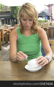 Pretty blond girl pulling a face because her coffeecup is empty