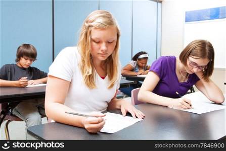Pretty blond girl taking a test with her high school class.