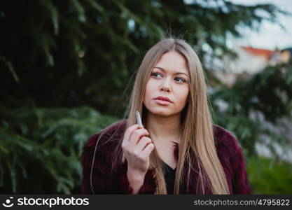 Pretty blond girl with long hair smoking in the park