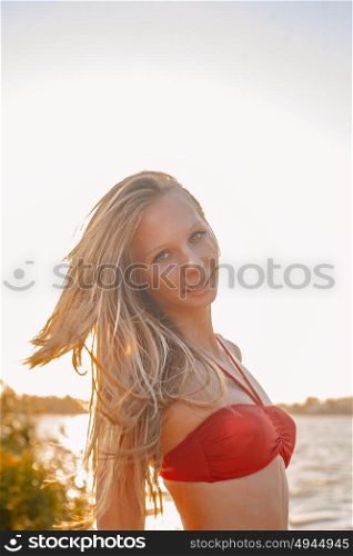 Pretty blond haired woman in red bikini top part on sunny beach