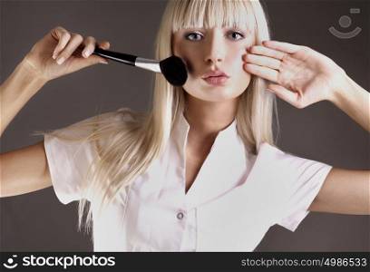 Pretty blond lady holding a makeup brush