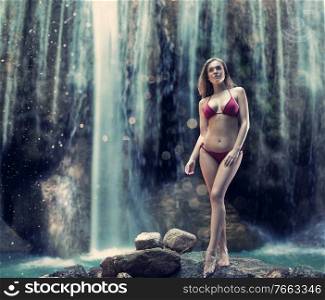 Pretty blond lady posing over the tropical waterfall