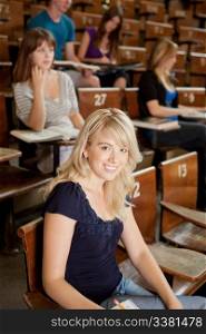 Pretty blond student in lecture theater looking at camera