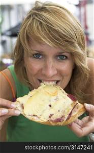 Pretty blond woman enjoying a good bite of her hot sandwich